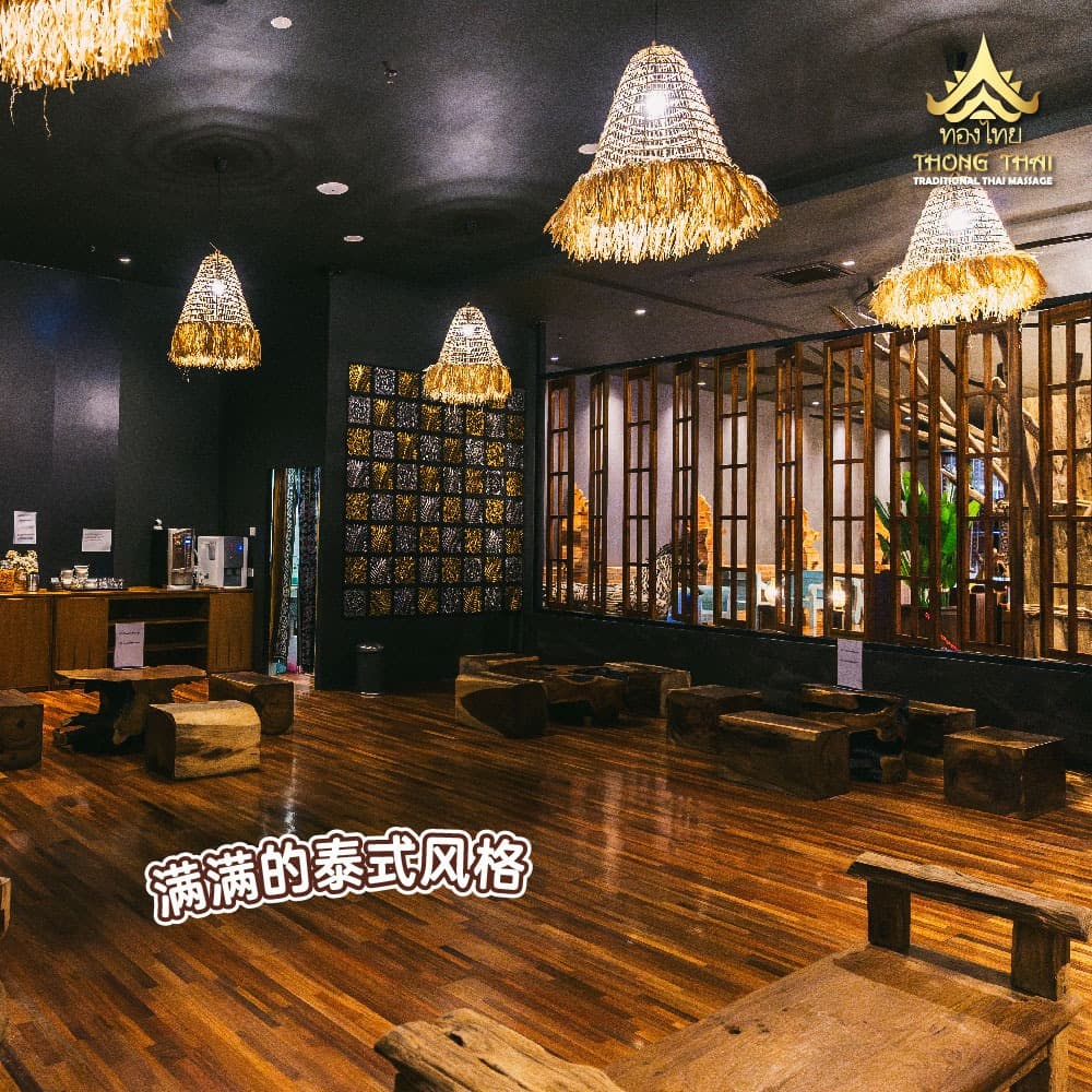 Dimly lit Thai massage interior with wooden floors, rustic benches, and large fringed straw lamps.