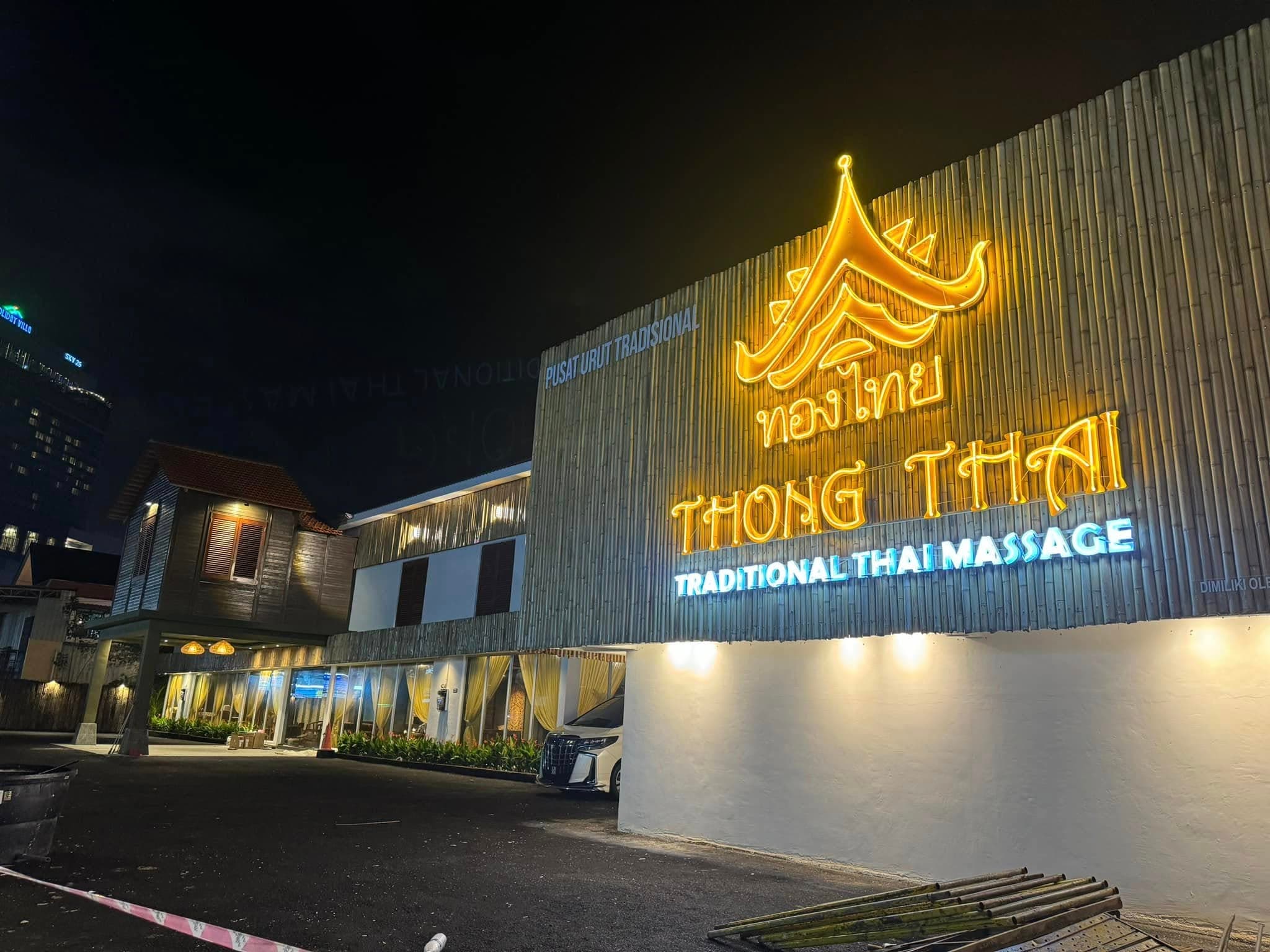 Thong Thai Traditional Thai Massage storefront at night with glowing yellow and blue neon signs.
