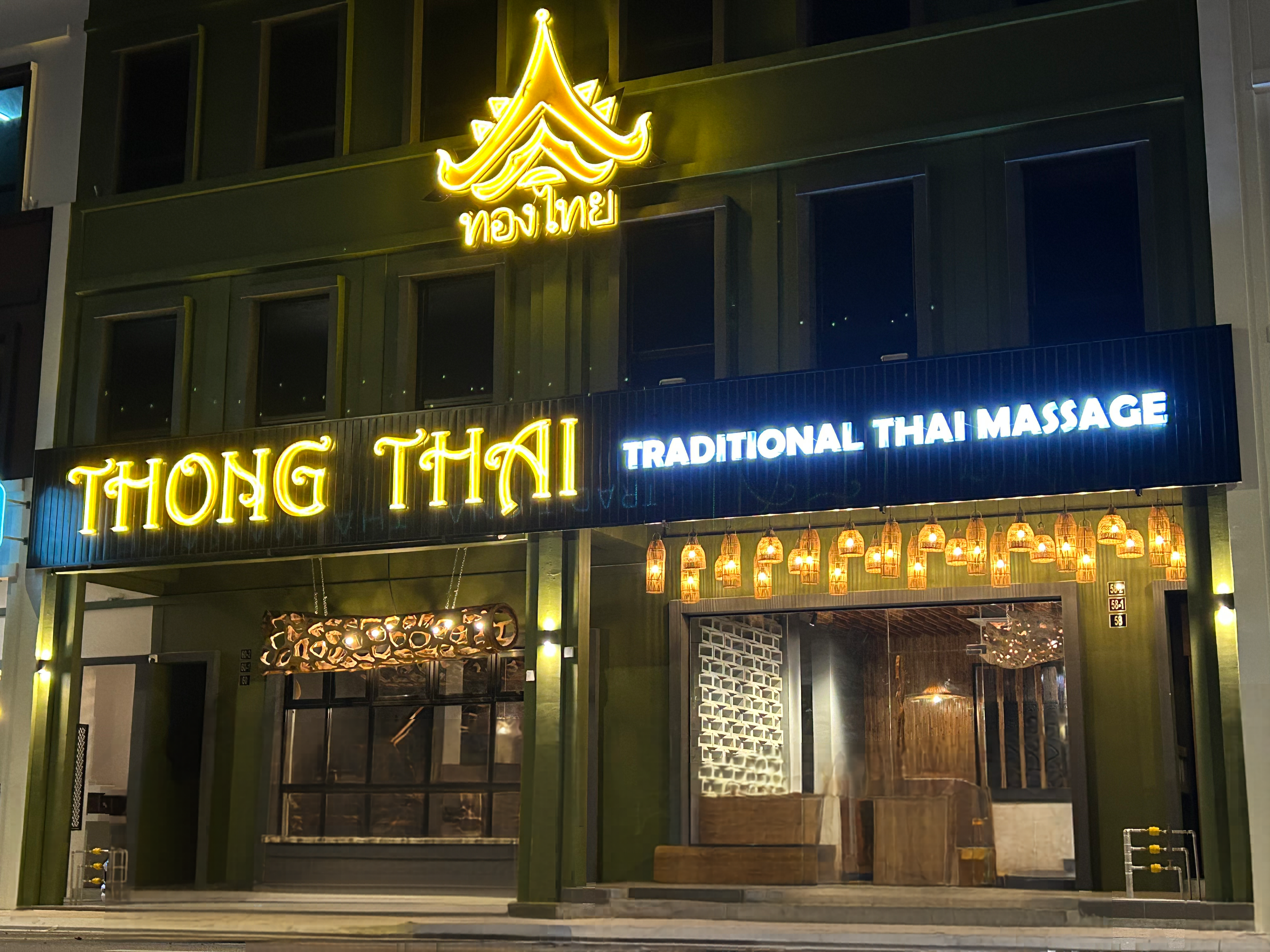 Thong Thai Traditional Thai Massage storefront at night with glowing neon signs and warm lanterns.